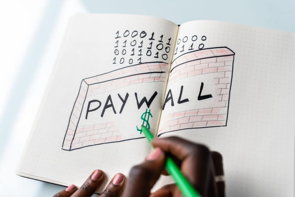 A hand-drawn brick wall with the text "Paywall" on the front and 0s and 1s behind it.