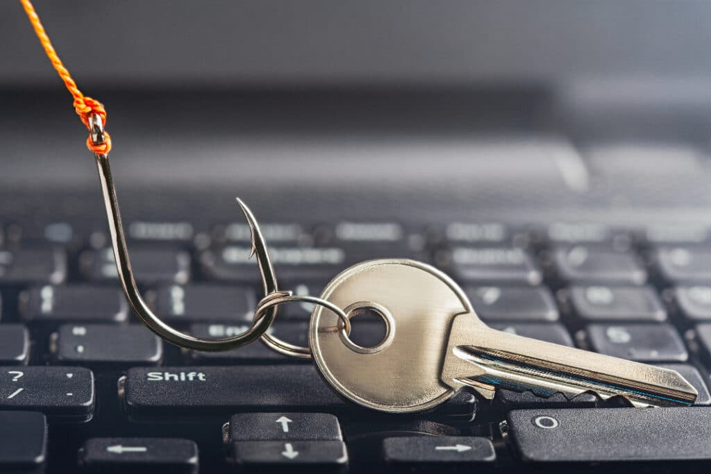 A key on a phishing hook, laying on a keyboard.