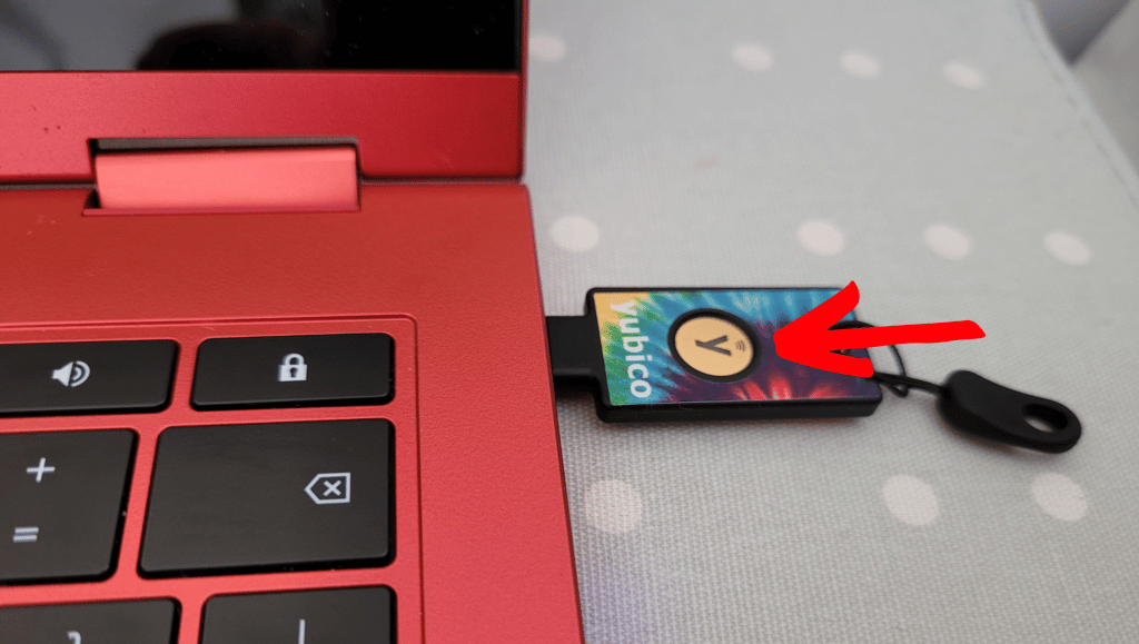 A YubiKey plugged in to the USB port on a red laptop