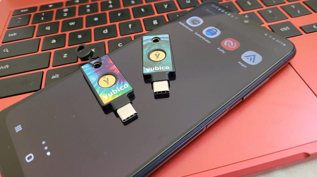 Two YubiKeys sit on an Android phone with different authenticator apps installed.