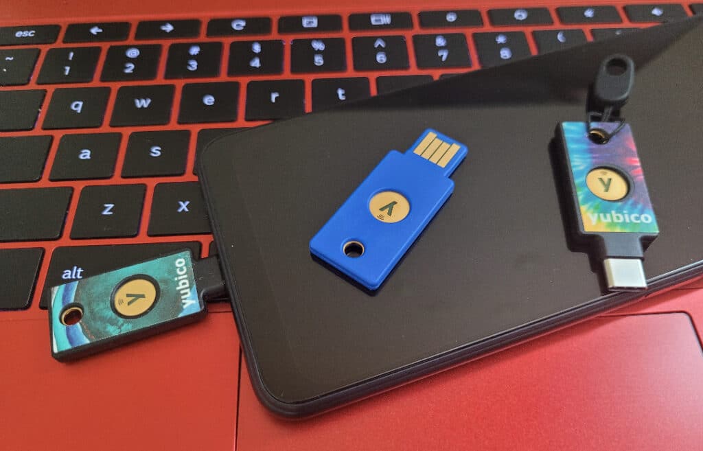 One YubiKey is plugged into an Android phone, while two YubiKeys are sitting on top of the phone.