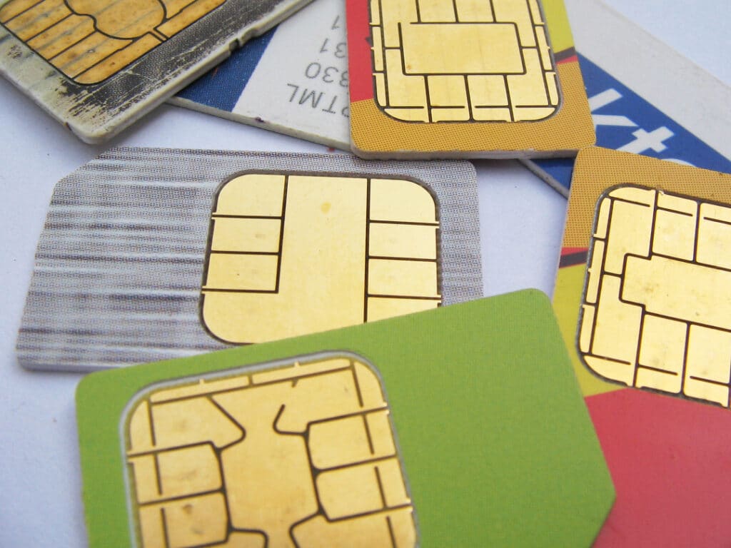 Many different colored SIM-cards strewn about on a surface.