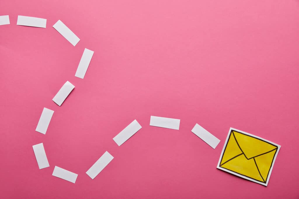 A paper cut out of a yellow mail envelope on a pink background