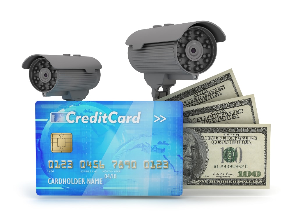 Two surveillance cameras stand watch over a credit card and some cash.
