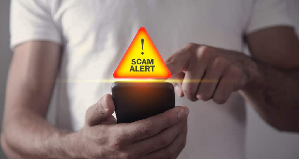 Man holding smartphone. Scam Alert