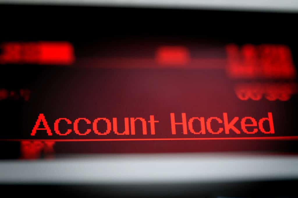 The message "Account hacked" is displayed in red on a computer screen.