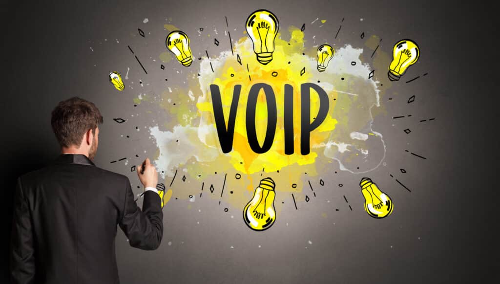 A man draws the word "VOIP" surrounded by bright lightbulbs.