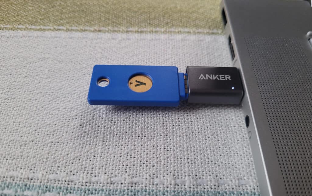 A blue Yubikey Security Key plugged into a Windows laptop using an adapter.