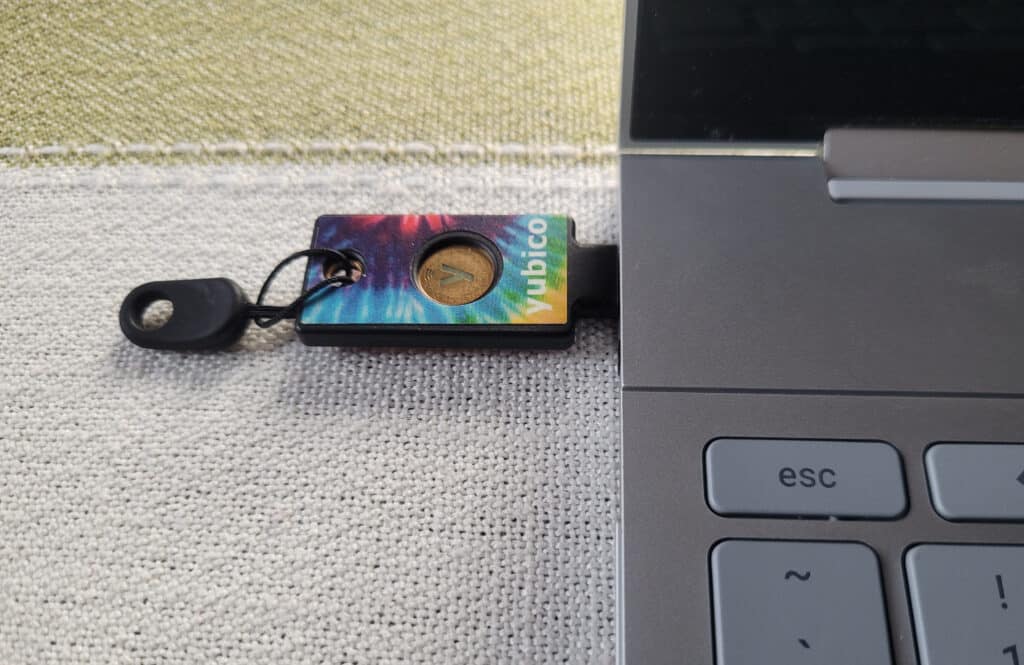 A rainbow colored Yubikey plugged into a Chromebook.
